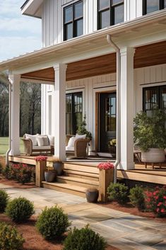 the front porch is covered with white pillars and wooden steps that lead to an outdoor seating area