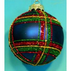 a christmas ornament hanging on a blue wall with red, green and gold stripes