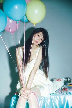 a woman sitting on top of a bed holding balloons