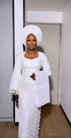 an african woman in white dress and headdress holding a paper bag with her hand