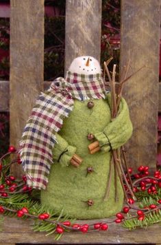 a small green snowman sitting on top of a wooden bench