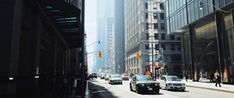 several cars are driving down the street in front of tall buildings on a sunny day