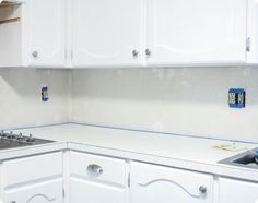 a kitchen with white cabinets and blue tape on the backsplash