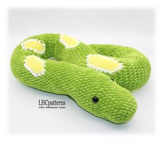 a green snake stuffed animal laying on top of it's back with yellow eyes