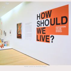 an orange and black sign hanging on the wall next to a white wall with pictures