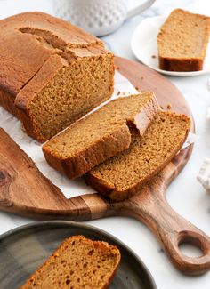 sliced loaf of pumpkin bread sitting on top of a cutting board next to two plates