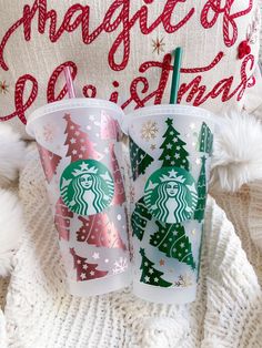 two starbucks cups sitting next to each other on top of a white blanket in front of a christmas pillow