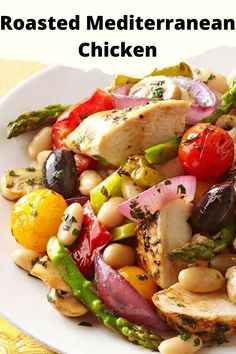 a white plate topped with chicken, asparagus, tomatoes and other veggies