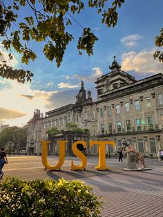 the word ust spelled out in front of a large building with people walking around