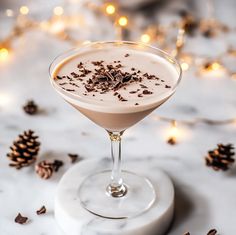 a drink in a martini glass garnished with chocolate shavings and pine cones