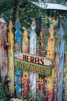 a wooden sign that says herbs and tomatoes painted on the side of a picket fence