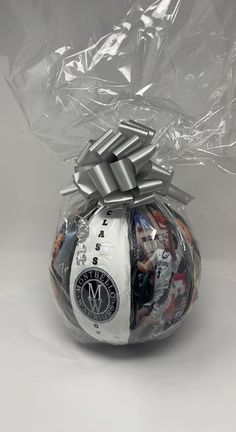 a ball wrapped in plastic and tied with a silver ribbon on the top is shown