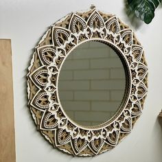 a round mirror hanging on the wall next to a potted plant