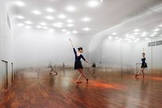 a group of people in a room with mirrors on the wall and one person dancing