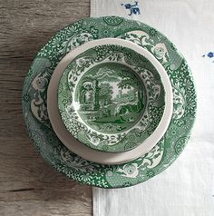 three green and white plates sitting on top of a wooden table next to each other