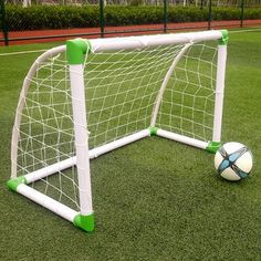 a soccer ball sitting on top of a green field next to a white goal post