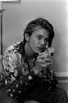 a man sitting on the floor holding a donut in his hand and looking at the camera