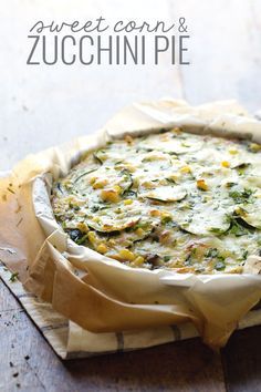 a pie with cheese and vegetables in it on top of a piece of parchment paper