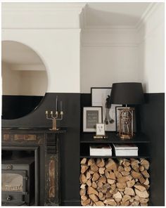 a fireplace with logs stacked on top of it next to a mirror and other items