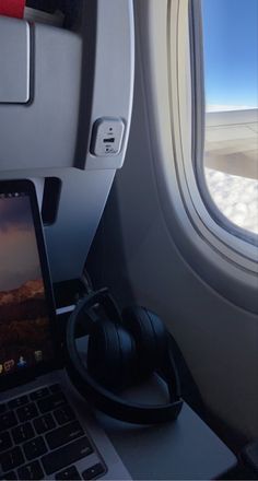 a laptop computer sitting on top of an airplane window