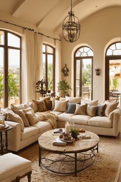 a living room filled with lots of furniture next to large windows and a chandelier hanging from the ceiling