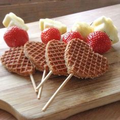 several waffles with strawberries and bananas on them sitting on a cutting board