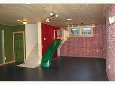 an empty room with a green slide in the center and red bricks on the walls