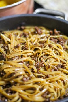 a pan filled with noodles and meat on top of a stove