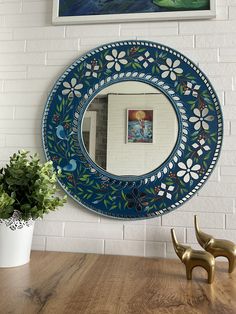 a mirror sitting on top of a wooden table next to a potted plant