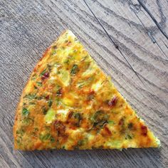 a slice of pizza with broccoli and cheese sitting on top of a wooden table