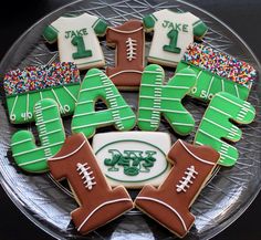 decorated cookies in the shape of footballs and jerseys on a plate with sprinkles