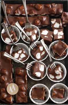 chocolate desserts are arranged in small bowls with forks and spoons on them, ready to be eaten