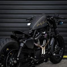 a black motorcycle parked in front of a garage door with graffiti on the side of it