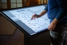 Close-up image of a person interacting with an Ideum Drafting Table. The person is using a stylus to make notes on the technical drawing visible on the screen of the touch table. Multitouch Table, Gamer Room Diy, Drafting Tables, Architecture Engineering, System Architecture, Art Studio Room, Architectural Engineering, Drafting Table, Touch Table