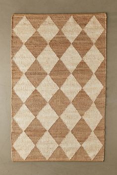 a brown and white area rug with squares on the bottom, in front of a wall