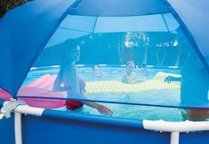 two people in a swimming pool with an umbrella over the water and one person sitting on a raft