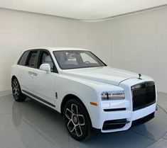 a white rolls royce parked in a large room with no one around it on the floor