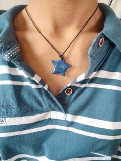 a woman wearing a blue and white striped shirt with a star pendant on her neck