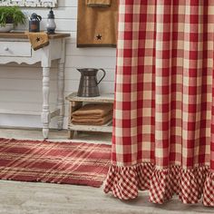 a red and white checkered shower curtain with ruffles on the bottom, in a bathroom