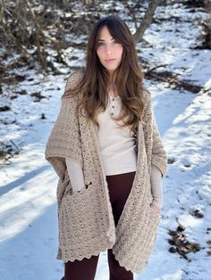 a woman standing in the snow wearing a cardigan