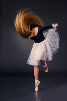 a young ballerina in a white tutu and black leotard is dancing