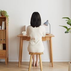 a woman sitting at a desk with a lamp on it