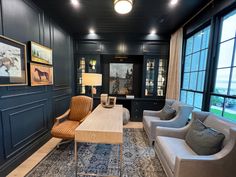 a living room with couches, chairs and pictures on the wall in front of large windows