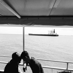 two men kissing each other on a boat in the ocean with a ship in the background