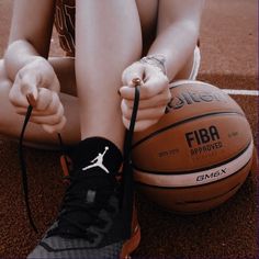 a person sitting on the ground next to a basketball with their hands in front of them