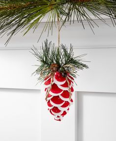 a pine cone ornament hanging from a christmas tree with red and white decorations