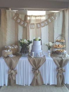 a table topped with a cake next to a window covered in burlaps