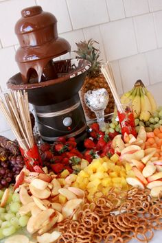 a table topped with lots of different types of fruit next to a fountain filled with chocolate