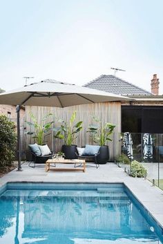 an outdoor pool with lounge chairs and umbrella