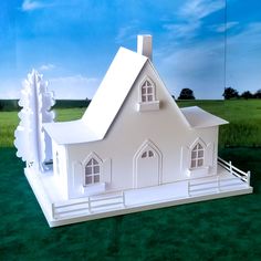 a paper model of a white house on green grass